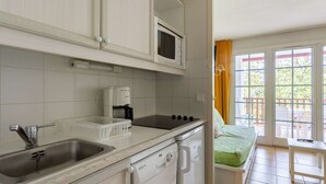 A compact kitchen with a sink, a coffee maker, a microwave, and a dishwasher.