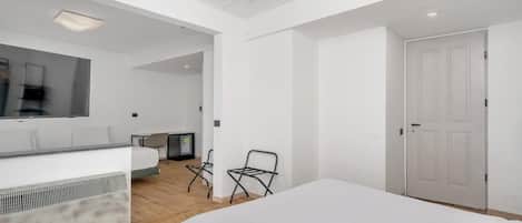 Un dormitorio moderno con una cama grande, un escritorio, una silla y un armario.