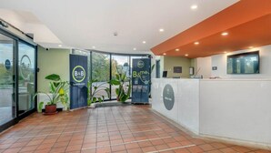 A hotel reception area with a tiled floor, reception desk, and potted plants. - B&B Hotel Alba (Alba)