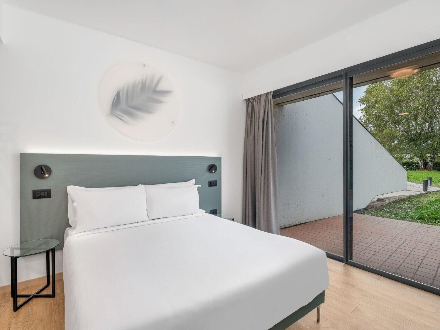 Un dormitorio moderno con una cama grande, una mesa de vidrio y vistas al exterior.