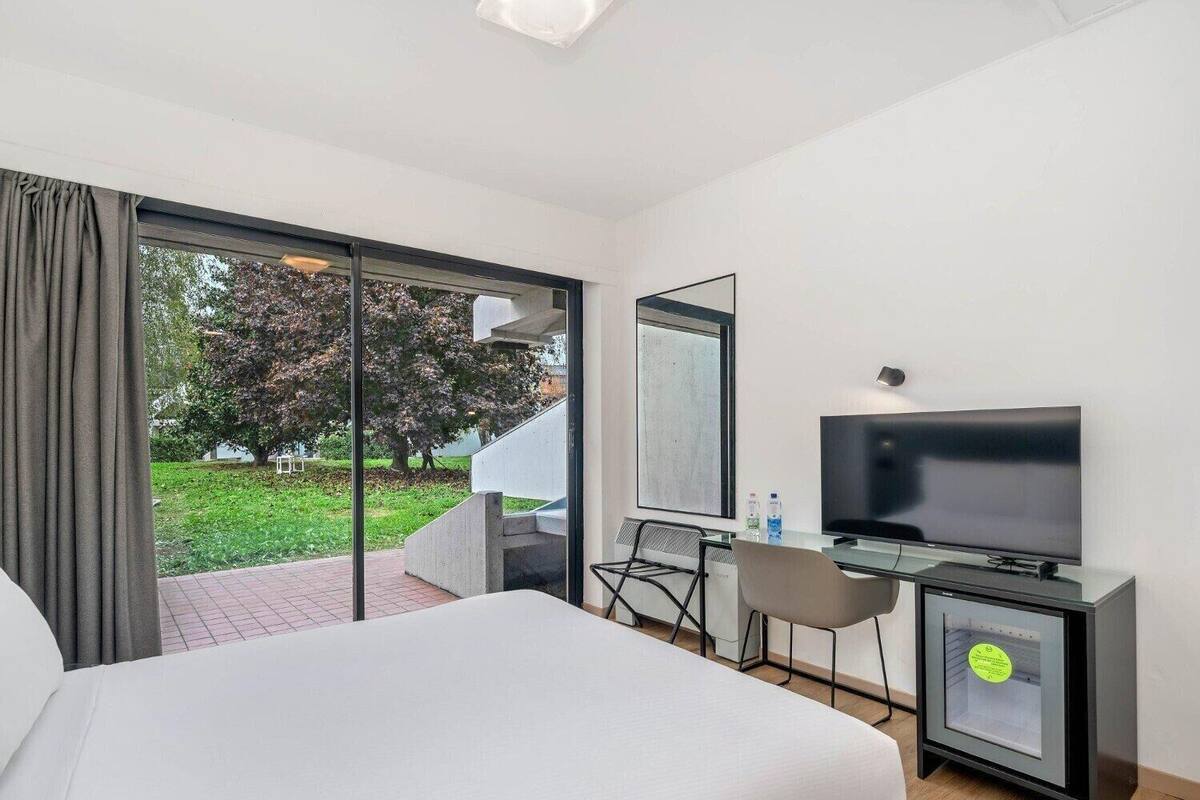 Une chambre d’hôtel comprenant un lit, un bureau avec une chaise, une télévision et un minibar.