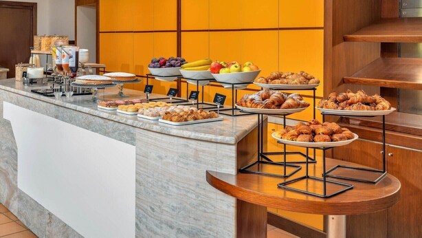 A buffet counter with various food items, including fruits, pastries, and a coffee station. - B&B Hotel Alba (Alba)