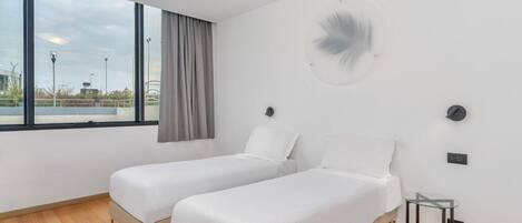 Una habitación de hotel moderna con dos camas individuales, un ventanal grande y vistas al exterior.