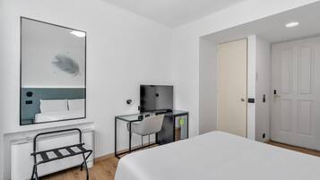 Ein modernes Hotelzimmer mit Bett, Schreibtisch, Stuhl, Spiegel und Tür.