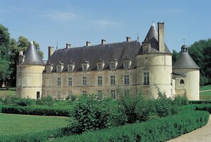 Een groot, historisch gebouw met meerdere torens en een verzorgde tuin.