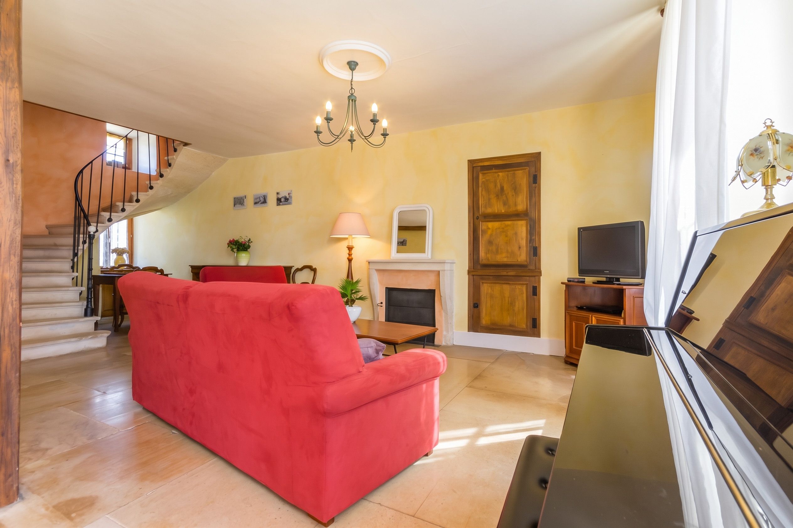 A living room with a red sofa, a fireplace, a television, and a staircase.