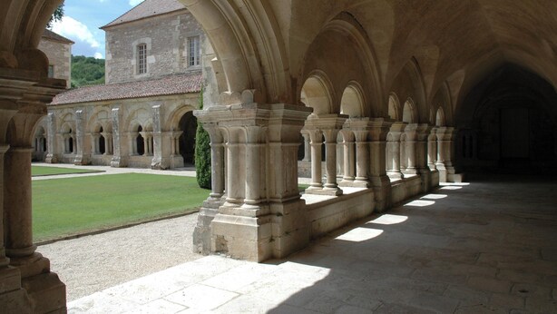 A courtyard with stone columns and arches, a building in the background, and a well-maintained lawn. - Homerez - House in Éringes, parking included (Éringes)