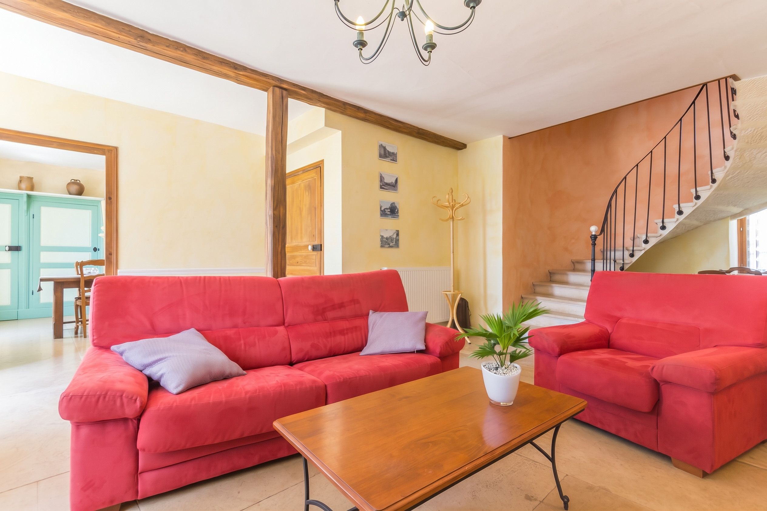 Un salon avec deux canapés rouges, une table basse en bois et un escalier doté d’une rampe.
