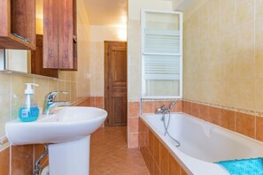 Een badkamer met een wastafel, kraan en een bad.