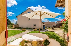 A patio with a table and chairs, a large umbrella, and a house in the background.