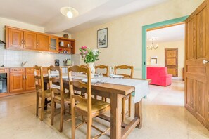 Een eetgedeelte met houten meubels, een tafel gedekt voor vier personen, en een keuken op de achtergrond.