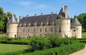 A large, historic building with multiple towers and a well-maintained garden.