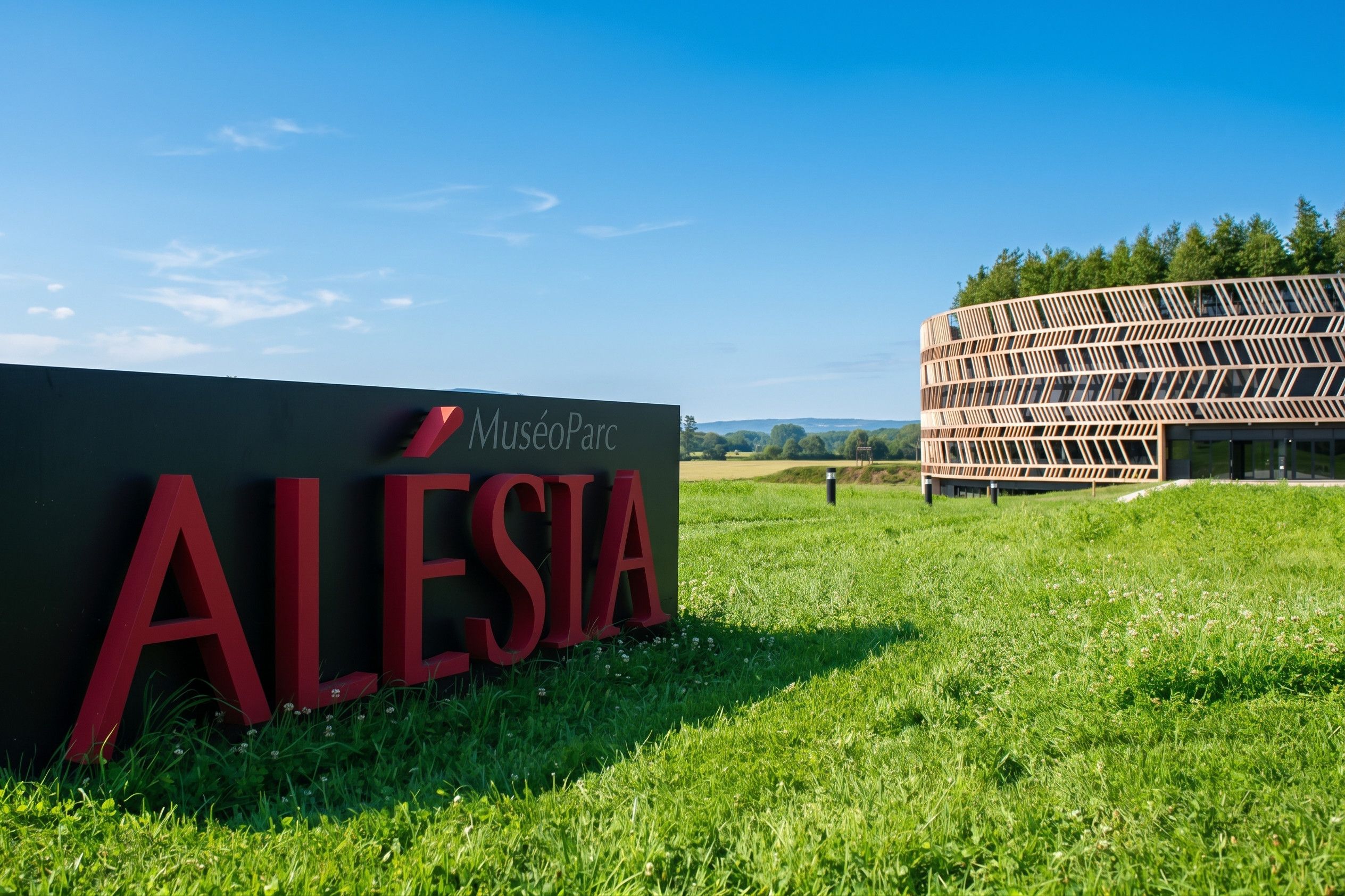 A sign for Museu Parc Alesia with a modern building in the background.