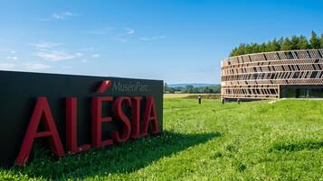 A sign for Museu Parc Alesia with a modern building in the background.