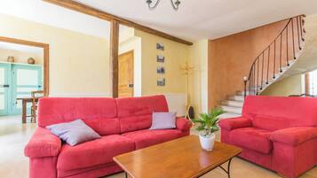 Ein geräumiges Wohnzimmer mit zwei roten Sofas, einem Holztisch und einer Treppe, die zu einer oberen Etage führt.