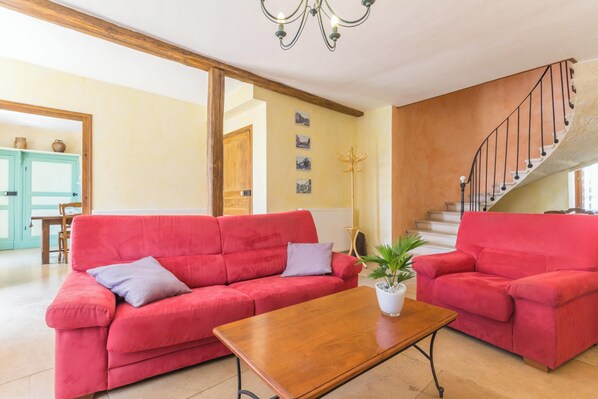Ein geräumiges Wohnzimmer mit zwei roten Sofas, einem Holztisch und einer Treppe, die zu einer oberen Etage führt.