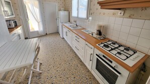 Een kleine keuken met een gasfornuis, een magnetron en een koelkast.