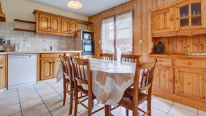 A wooden-paneled kitchen with a dining table, chairs, and a dishwasher. - Sermes 1 - Spacious apartment in the centre (MORZINE)