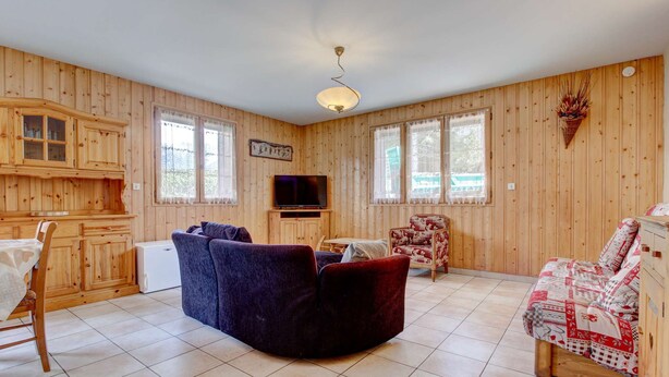 A wooden-paneled room with a sofa, a bed, a TV, and a dining area. - Sermes 1 - Spacious apartment in the centre (MORZINE)