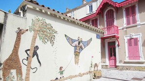 Un bâtiment orné d’une fresque représentant une girafe, un arbre et un ange.