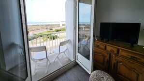 Un balcon avec vue sur la mer et un téléviseur posé sur un meuble en bois.