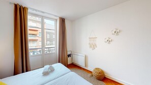 A hotel room with a bed, a radiator, a window with curtains, and a wall with decorative items. - netter 70m2 city center    2br (Strasbourg)