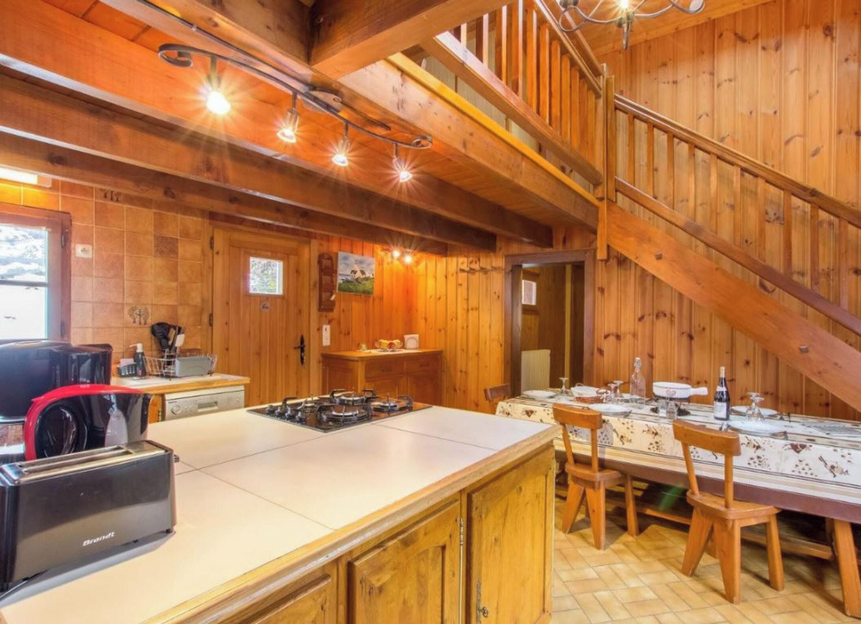 Una cucina rustica con interni in legno, una stufa a gas, un lavello e un'area pranzo con tavolo imbandito per quattro persone.