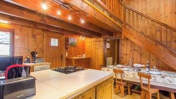 Una cucina rustica con interni in legno, una stufa a gas, un lavello e un'area pranzo con tavolo imbandito per quattro persone.