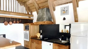 Eine Küche mit Holzausstattung, einer schwarzen Arbeitsplatte, einem Herd, einer Spüle und einem Kühlschrank.