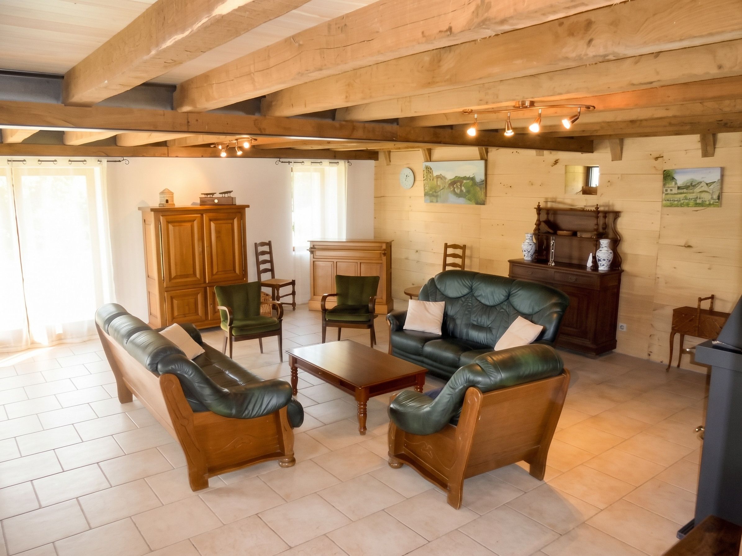 A cozy living room with wooden furniture, a green sofa, a wooden coffee table, and a dining area with a wooden table and chairs.