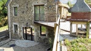 Ein Steinhaus mit Balkon, einer Holzterrasse und einem Steinkamin.