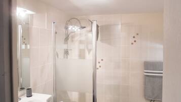 Ett badrum med en dusch som är avskärmad med glasväggar, ett handfat och en handduksställning.