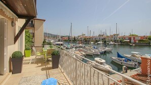 A balcony with a view of a marina, outdoor seating, and potted plants. - Lovely renovated flat for 4 persons with AC and mooring (PORT GRIMAUD)