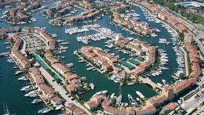 An aerial view of a marina with numerous boats docked, surrounded by residential buildings with red-tiled roofs. - Lovely renovated flat for 4 persons with AC and mooring (PORT GRIMAUD)