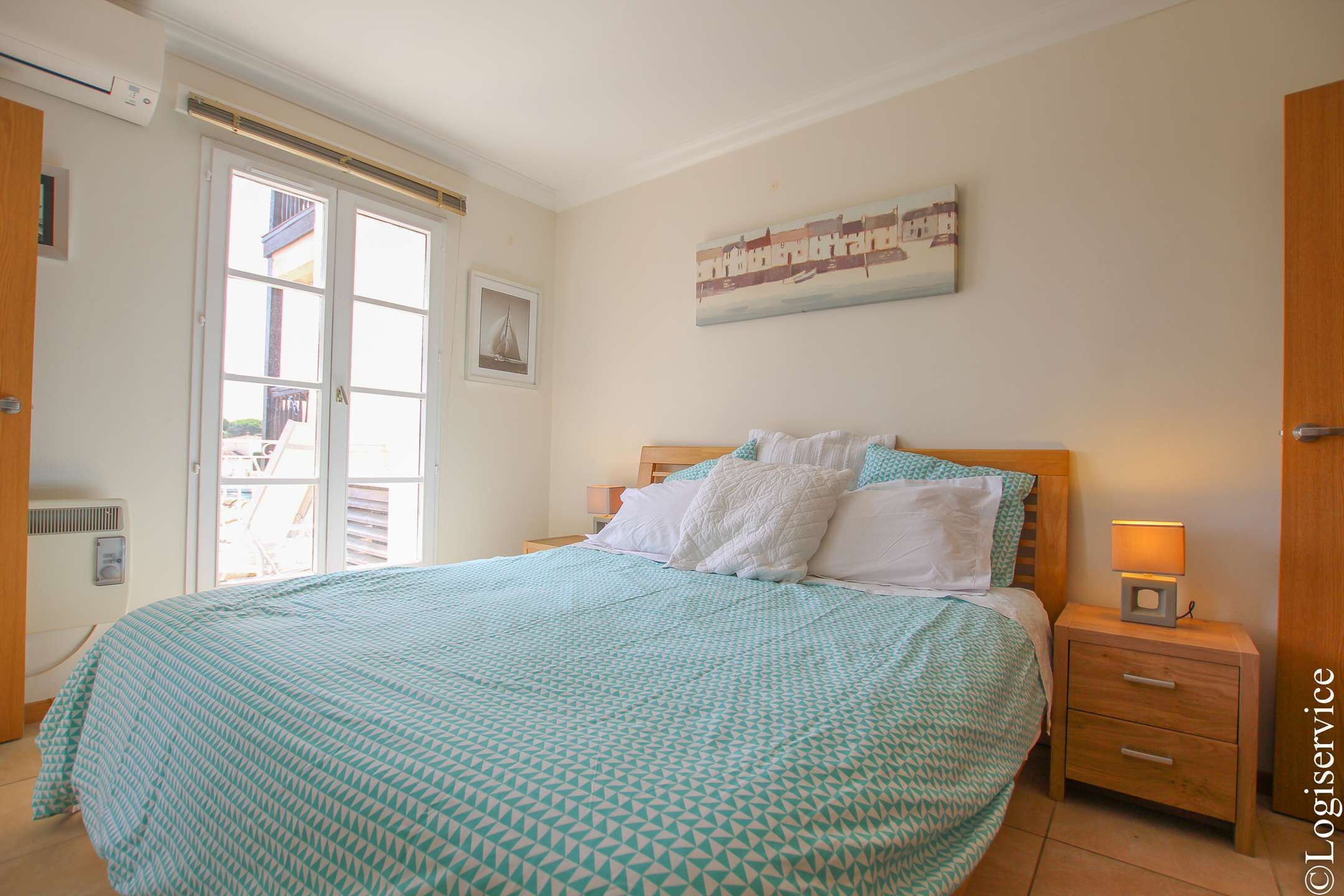 Ein Schlafzimmer mit Bett, Nachttisch, Fenster und Tür.