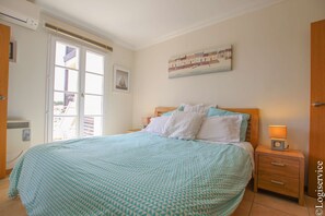 Une chambre à coucher avec un lit, une table de chevet, une fenêtre et une porte.