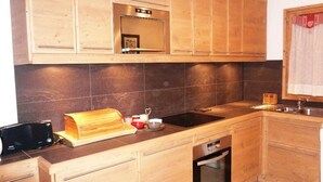 Cozinha moderna com armários de madeira, bancada preta, forno embutido e pia.