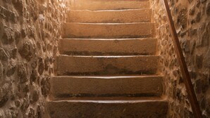 Eine steinerne Treppe mit hölzernem Geländer, die nach oben führt.