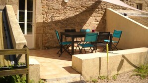 Eine Terrasse im Freien mit einer Steinmauer, einem Tisch und Stühlen sowie einem weißen Baldachin.
