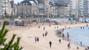 A beach with people walking and playing, surrounded by buildings. - Elegant Apartment with Garage – 400m from Beach (Les Sables-d'Olonne)