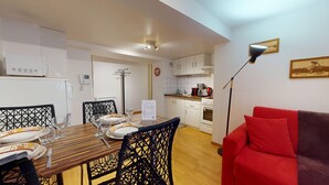 Un espace de vie compact comprenant un coin repas, une kitchenette et un canapé rouge.
