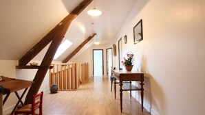 Un loft amplio con techos altos, vigas de madera a la vista, una mesa de comedor de madera y una escalera que sube a un nivel superior.