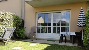 Un patio con una mesa, sillas y una tumbona.