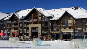 A multi-story hotel with a stone facade, balconies, and a ski resort in the background. - Apartment 6 ppl, balcony, ski-in/ski-out, parking, spa - Peyragudes (Peyragudes)
