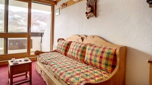 A cozy room with a wooden bench and a small table, a large window with a view of mountains, and a welcome sign on the wall. - Bright ski-in/ski-out duplex, balcony, 4 ppl (Les Menuires)