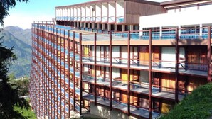 Et hotel med flere etager, altaner og udsigt til bjergene.