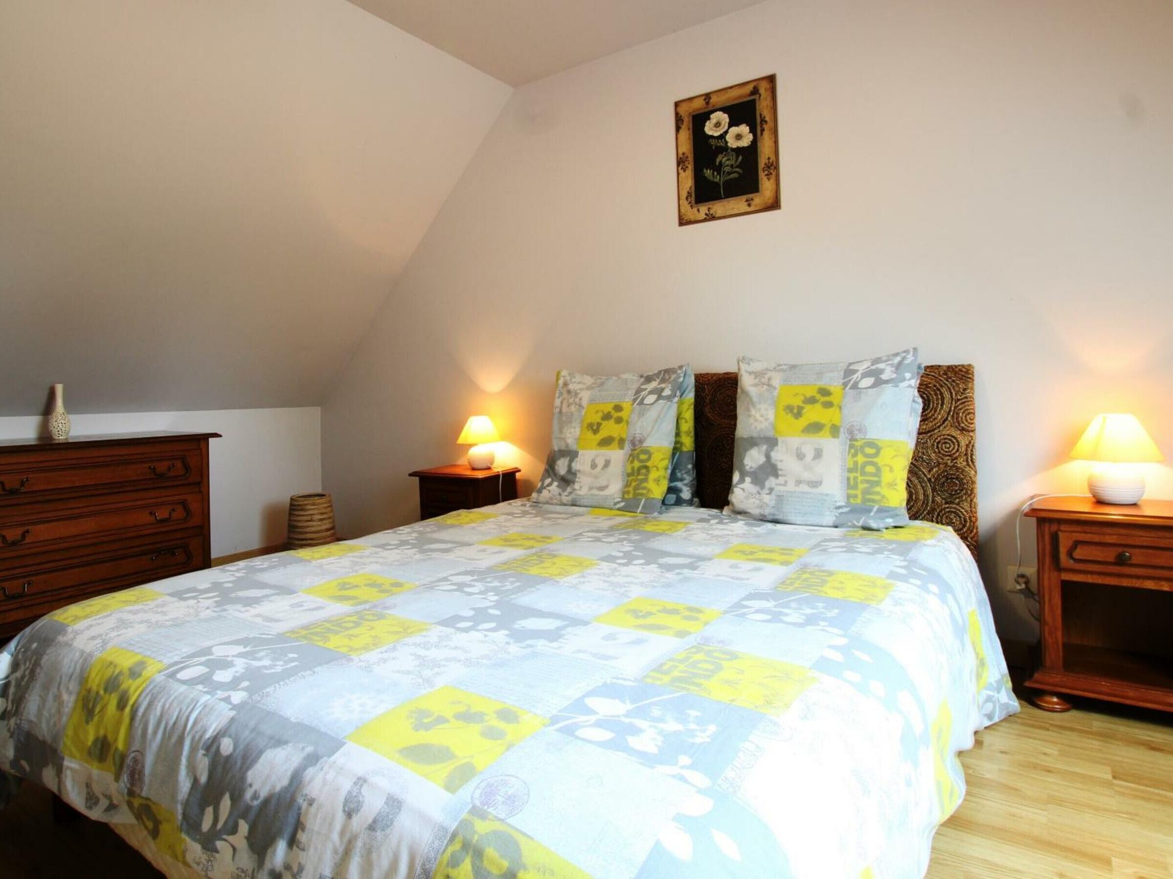 Une chambre à coucher comprenant un lit, deux tables de chevet, une commode et un tableau accroché au mur.