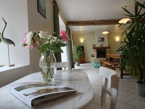A living room with a marble table, a vase with flowers, a fireplace, and a television. - Bright house with fireplace and enclosed garden (Le Plessis-Lastelle)