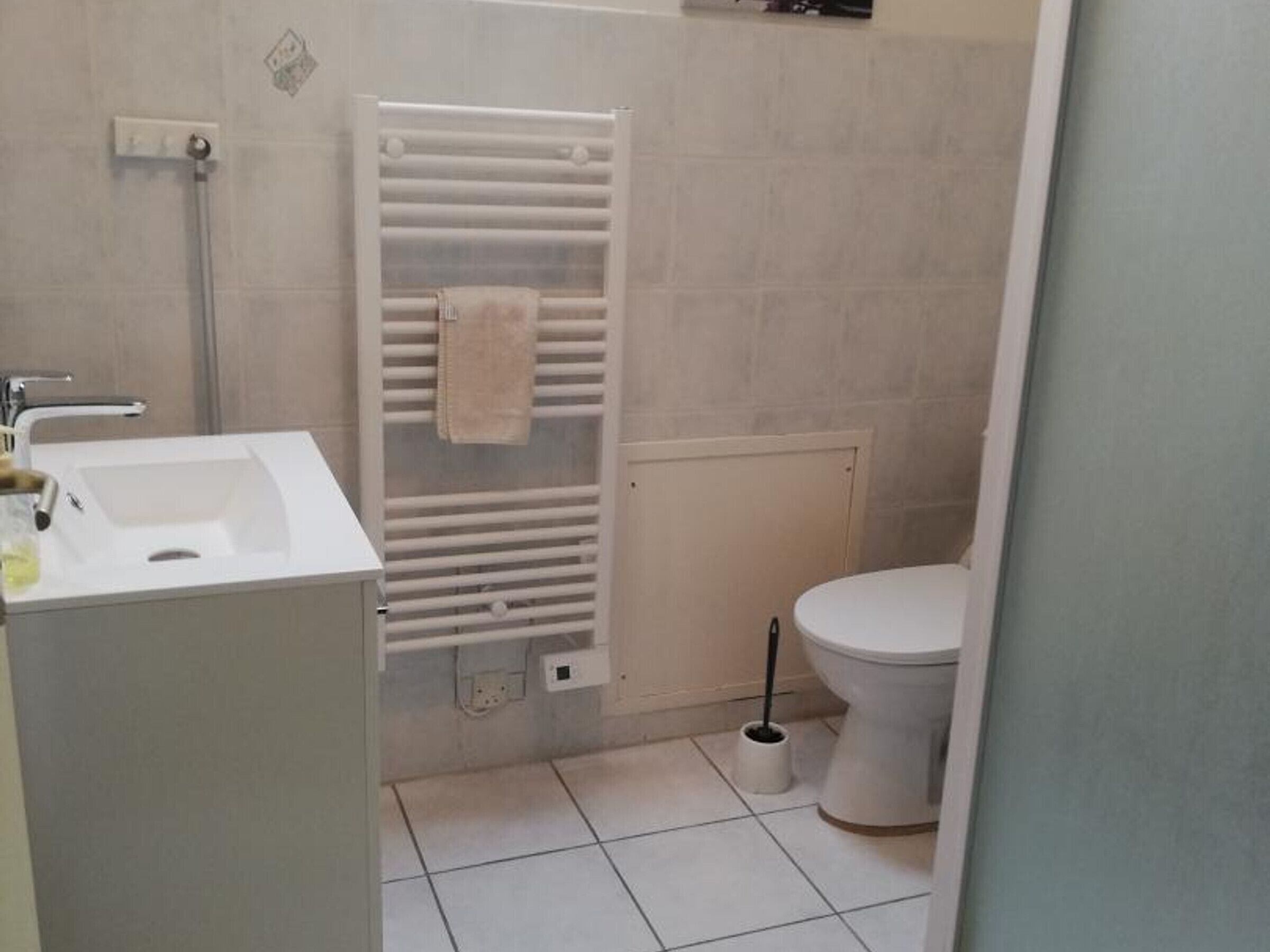 Un baño con lavamanos, inodoro y perchero para toallas.
