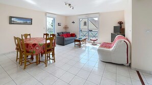 Amplia sala de estar con mesa de comedor, sillas, sofá y mueble para televisión.